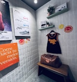 A small retro-themed display with a focus on athletic apparel and shoes. The walls feature a series of posters showcasing various Nike shoes from different years. A black gym tank top and a brown leather gym bag are prominently positioned on a wooden bench. There are decorative elements like potted plants on wall-mounted shelves and smiley face icons. The environment has a nostalgic and sporty atmosphere.